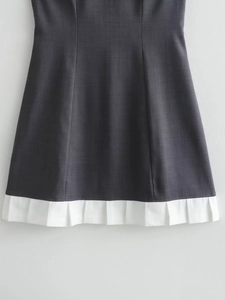Detail of dark grey sleeveless dress showing white pleated hem with woven texture