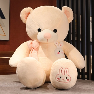 Detail of soft cream teddy bear plush with pink silk bow and cute rabbit embroidery