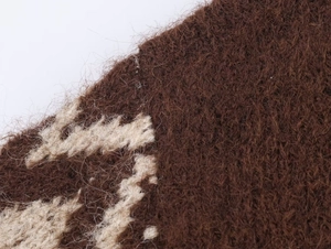 Dettaglio macro del tessuto a maglia marrone scuro con trama in mohair e motivo jacquard beige