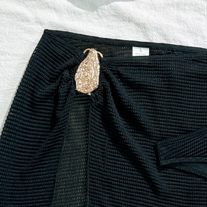 Detail of black mesh bikini skirt with a gold metallic buckle and wash label S size
