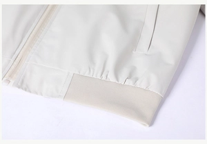 Detailed view of the jacket zipper, side pocket, and ribbed hem in light beige fabric