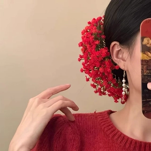 Dettaglio accessorio capelli floreale rosso e orecchini di perle abbinati da donna