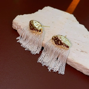 Gros plan sur les boucles d'oreilles dorées à franges sur pierre blanche marbrée