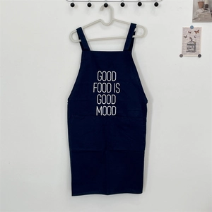 Detail of navy canvas apron featuring 'GOOD FOOD IS GOOD MOOD' text and durable pocket