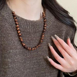 Close-up of tiger eye beaded necklace with cat eye effect on vintage brown sweater
