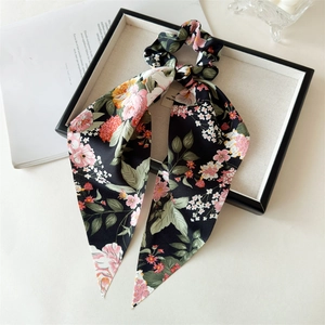 Detail of satin floral print hair scrunchie with long ribbons on a display tray