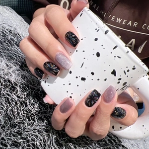 Cat eye press-on nails featuring 3D floral designs and purple glitter on a black base