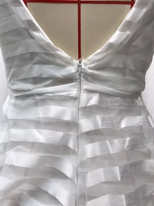 Dettaglio dell'abito da sposa bianco a balze con schiena a V profonda e zip invisibile