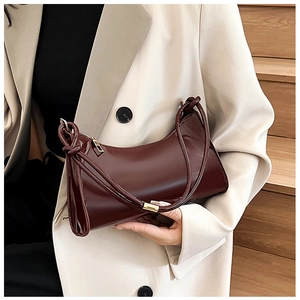 Close-up of deep burgundy crescent bag with glossy patent leather finish and gold hardware