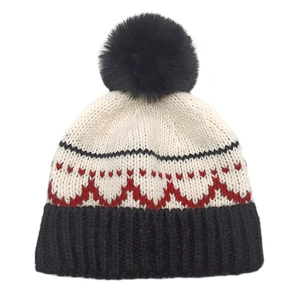 Dettaglio di un cappello invernale in maglia con pompon e motivo jacquard geometrico