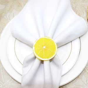 Detail of yellow lemon slice napkin ring on white fabric for summer table decor