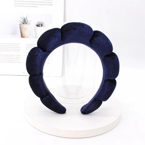 Close-up of deep blue velvet sponge headband with wavy cloud design on a display stand