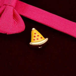 Close-up of a small gold pizza slice enamel pendant for DIY jewelry on red velvet