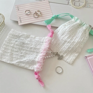 Close-up of small white polka dot drawstring pouches on desk with lifestyle accessories