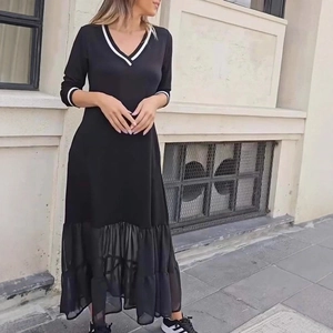 Détail d'une robe noire élégante avec col en V, ourlet en mesh et finitions rayées