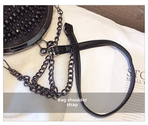 Detail of black leather strap and thick metal chain on a studded shell-shaped shoulder bag