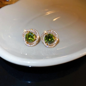 Macro shot of emerald green round gem earrings with gold spiral pave white rhinestones