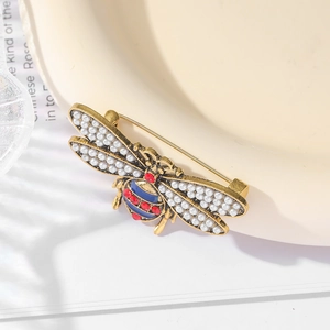 Vintage gold bee brooch with pearls and colorful rhinestones on ceramic tray