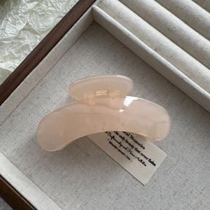 Close-up of translucent pink jelly hair claw clip in a wooden jewelry box display