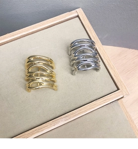 Detail of layered wavy metal rings in gold and silver finish on a display tray