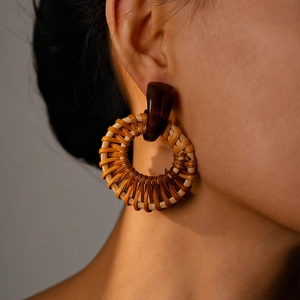 Close-up of bohemian handmade woven rattan hoop earrings with brown resin accents on model