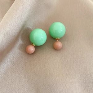 Detailed view of mint green and nude resin double-bead earrings on champagne silk fabric