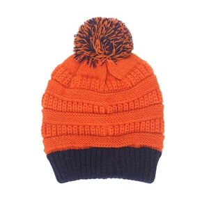 Détail du bonnet en tricot avec pompon bicolore contrasté orange et bleu en gros plan