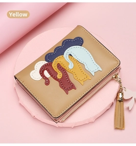 Detail of yellow short wallet featuring colorful cat silhouettes and tassel zipper closure