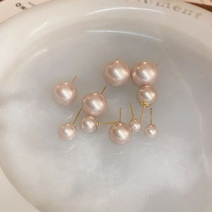 Close-up of pink pearl earrings set in a white ceramic bowl showing various sizes