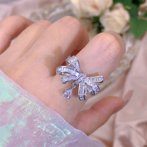 Detail view of silver bow ring with shimmering cubic zirconia and water drop pendant