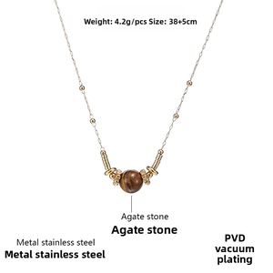 Macro detail of gold PVD plated stainless steel necklace with a round agate stone pendant