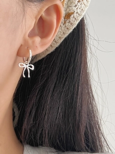 Close-up of minimalist sterling silver bow hoop earrings worn by a model