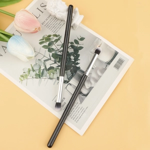 Detailed top view of double-ended eyeshadow brushes with black handles on a scenic background
