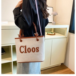 Detail of canvas tote bag with brown leather trim and Cloos logo on neutral background