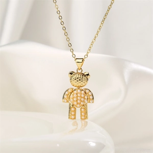 Macro detail of a golden bear necklace pendant with white pearls on a white silk background