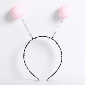 Detail of a black headband featuring metallic springs and pink glitter foam balls