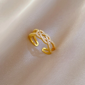 Detail of gold plated twisted cross ring with micro-pave zircons on champagne silk