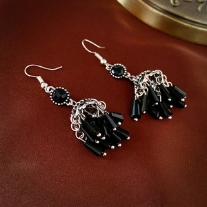 Detail of vintage ethnic drop earrings with silver metal hooks and black beaded tassels