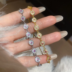 Close-up of gold and silver plated bracelets with sparkling zircons and pink center stones.