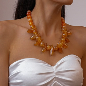 Detail shot of amber acrylic statement necklace with round beads and teardrop pendants