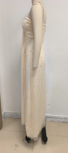 Dettaglio dell'abito da sera in tulle color albicocca con corpino a pieghe e perle bianche