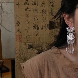 Detailed shot of silver hollow butterfly flower tassel earrings with vintage Chinese style