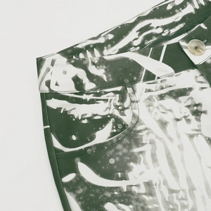 Detailed close-up of high-waisted dark green abstract print pants with button and stitching