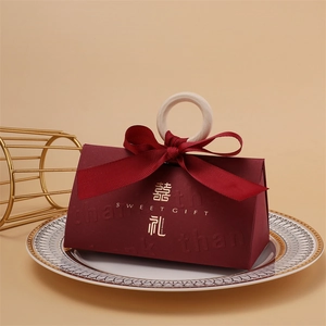 Detailed view of red wedding candy box with wooden handle, gold lettering, and silk ribbon