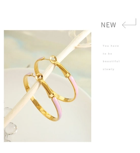 Detail of pink enamel and gold-plated titanium hoop earrings on a decorative branch