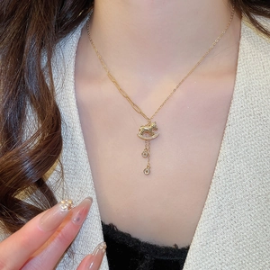Close-up of gold-plated horse pendant necklace with crystal accents worn by a model