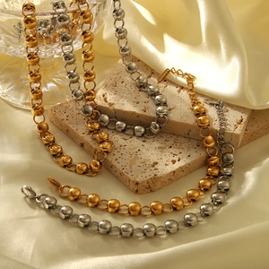 Close-up of gold and silver bead chain necklaces on silk and stone background