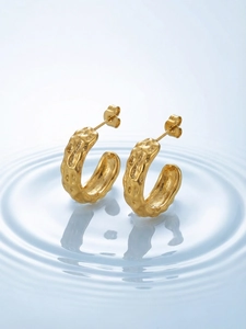 Detailed macro view of 18k gold plated C-shape hoop earrings with hammered texture surface