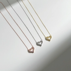 Close-up of heart-shaped pendant necklaces in gold, silver, and rose gold with pavé crystals
