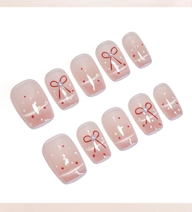 Détail d'ongles œil-de-chat roses avec nœuds rouges, perles et pois sur fond blanc pur